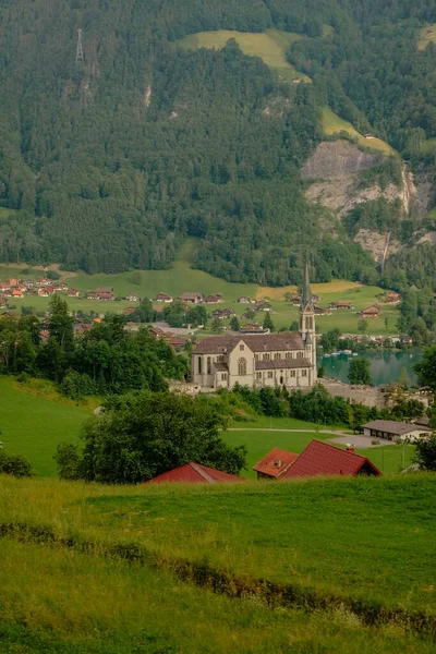 İsviçre 'nin Lungern köyünde geleneksel evleri ve eski kilise kulesi güzel zümrüt yeşili Lungerersee Gölü boyunca Alter Kirchturm, Obwalden kantonu, İsviçre Alpleri, Brunig Geçidi