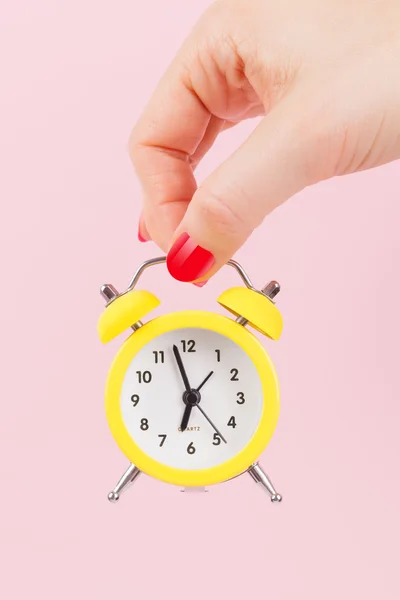 Mão feminina com despertador amarelo . — Fotografia de Stock