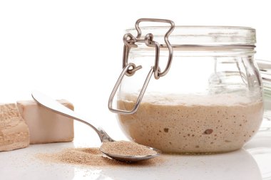 Kavanozda ekşi ekmek ve çeşitli maya türleri. Beyaz arkaplanda izole edilmiş taze ve kuru granüller.