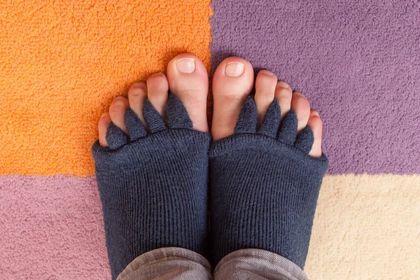 Bunion, hallux valgus. Finger toe separator socks on feet isolated on colorful carpet.