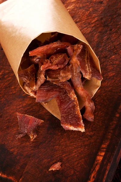 Dry meat beef jerky on wooden chopping board — Stock Photo, Image