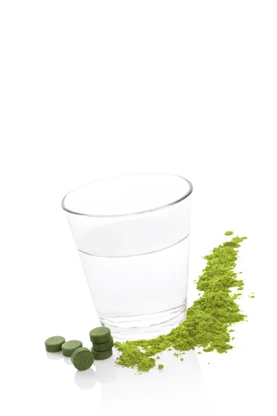 Grüne Nahrungsergänzungsmittel und ein Glas Wasser. — Stockfoto