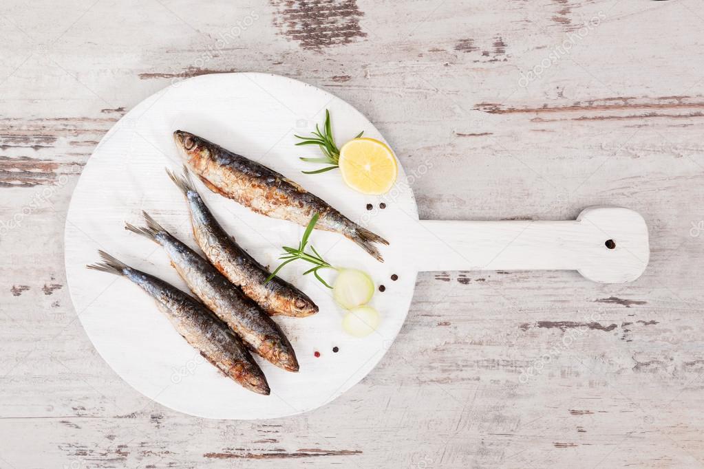 Grilled sardines on wooden plate.
