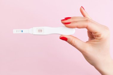female hand with red fingernails holding positive pregnancy test clipart