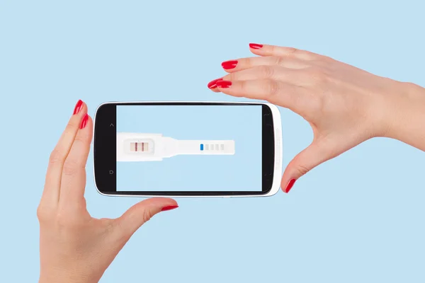 Holding smartphone with pregnancy test. — 图库照片