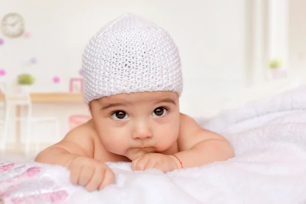 Lilla bebis på magen i en vit Stickad mössa Stockbild