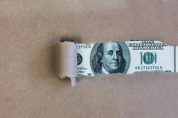 Доллары через рваную зеленую бумагу — стоковое фото