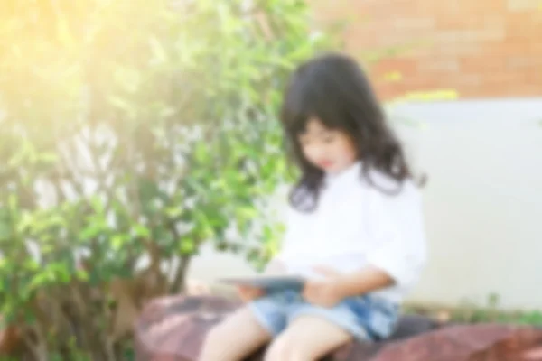 Ázsiai gyermek ül a kert tábla-PC játék — Stock Fotó