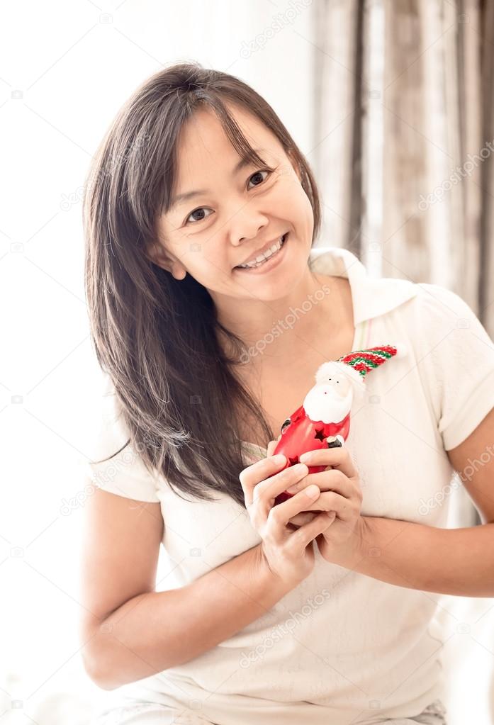woman in white clothes holding toy of Santa in hand