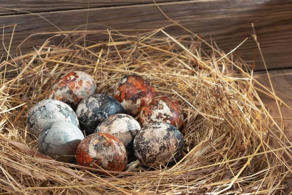 Composizione pasquale - uova di Pasqua in marmo multicolore dipinte con coloranti naturali in un nido di fieno — Foto Stock