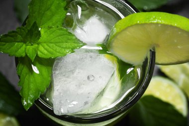 Kireç, nane ve buzlu taze ev yapımı mojito kokteyli. Siyah arka planda. Yakın plan.