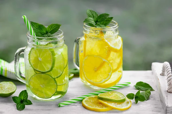 Холодный освежающий домашний лимонад с мятой, лимоном и лаймом в банках из каменщиков — стоковое фото