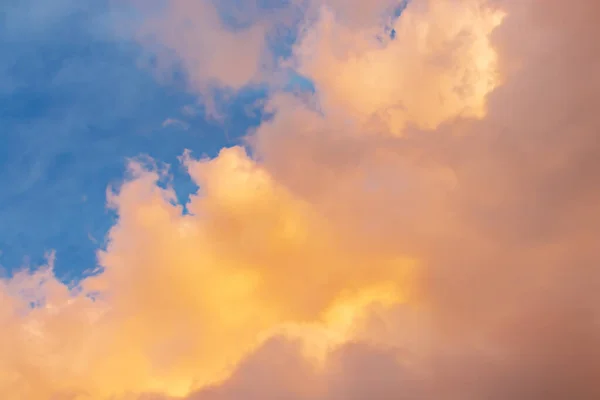 Schöne Wolkenlandschaft - rosa-orangefarbene Wolken in den Sonnenstrahlen gegen den blauen Himmel — Stockfoto