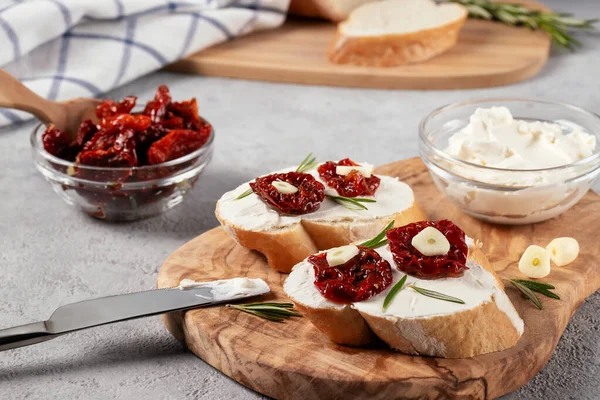 Zelfgemaakte broodjes met roomkaas en zongedroogde tomaten op een houten olijfplankje - heerlijk gezond ontbijt, Italiaanse keuken — Stockfoto