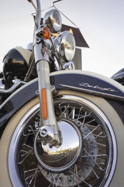 Klasik Harley Davidson motorsikletinin krom ön tekerleğinin ayrıntıları, beyaz duvar lastikleri ve retro tasarımı.