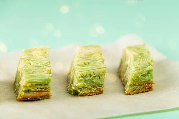 Pandan cake. Pieces of green cake with Pistachio nuts on paper. Korean dessert of Matcha tea. Vegan food