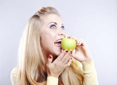 Yeşil elma ile gülümseyen kız. Geniş bir gülümseme. Sağlıklı dişler