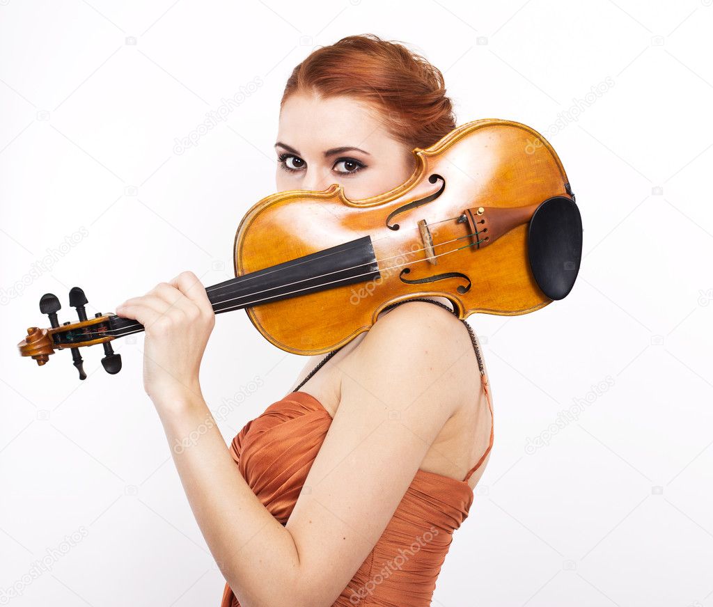 Young red-haired girl with a violin in her hands on a white background.evening dress.Long orange dress