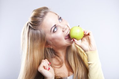 Yeşil elma ile gülümseyen kız. Geniş bir gülümseme. Sağlıklı dişler