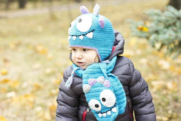 Happy baby i en rolig hatt på en promenad. Gångavstånd utomhus på hösten. Höstlöv — Stockfoto