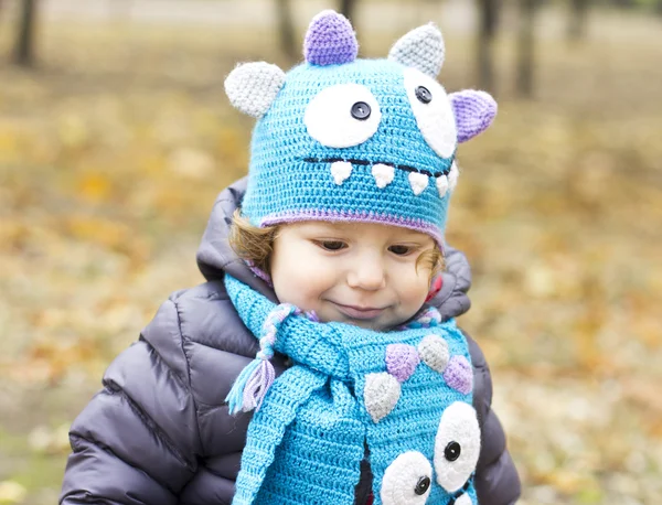 Happy baby in a funny hat on a walk. Walking outdoors in the fall. autumn leaves