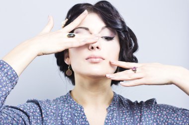 Gri bir arka plan üzerinde güzel esmer. Kirpik uzantıları. Dudak büyütme. tırnak uzatma