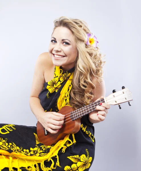 Jovem loira alegre em um cachecol havaiano. A rapariga joga ukulele. Estilo havaiano. Retrato de uma mulher sorridente — Fotografia de Stock