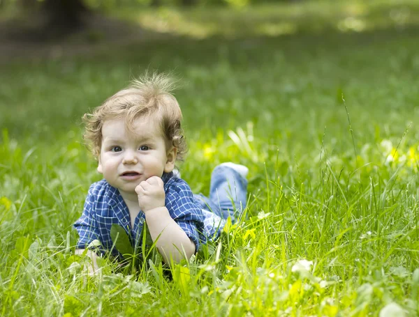 Schönes Kind, das im grünen Gras sitzt. Kind im Freien. Kinder gehen. Spaziergang mit dem Kind. Sommerferien — Stockfoto
