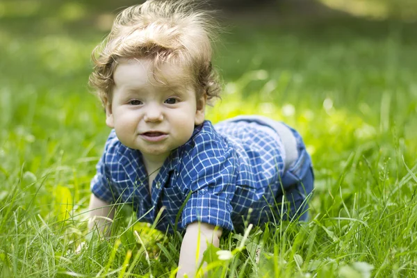 Schönes Kind, das im grünen Gras sitzt. Kind im Freien. Kinder gehen. Spaziergang mit dem Kind. Sommerferien — Stockfoto