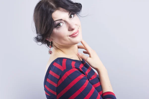 Beautiful girl in a striped dress. Smiling brunette on a black background. Portrait of smart woman — Stock Photo, Image