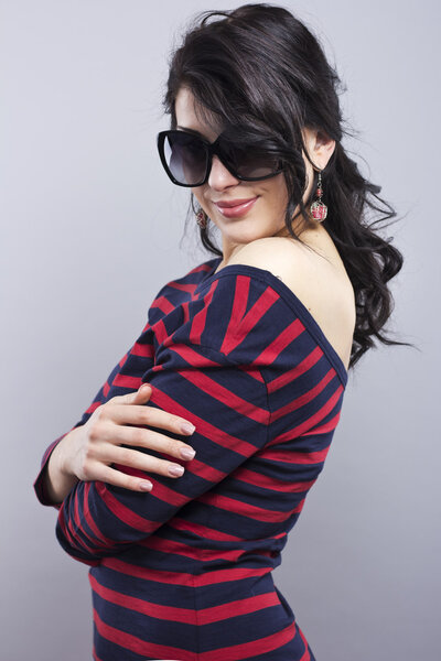 Beautiful brunette in a blue dress with red stripes. Fashion. Portrait of a young girl in sunglasses.