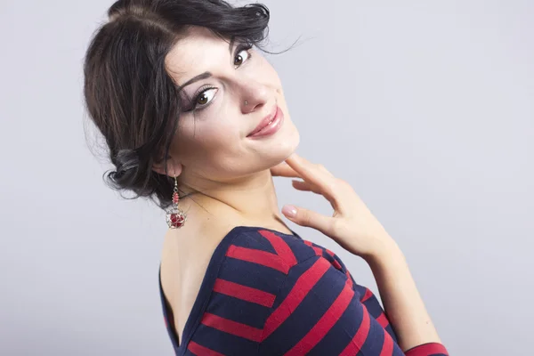 Beautiful girl in a striped dress. Smiling brunette on a black background. Portrait of smart woman — Stock Photo, Image