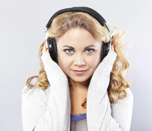 Una joven sonriente escucha música. Rubia en auriculares —  Fotos de Stock