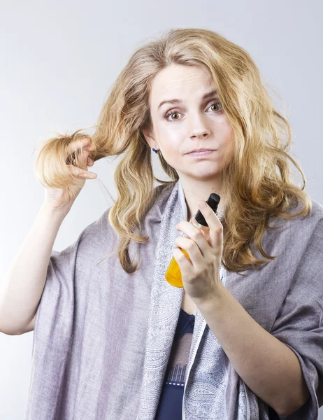 Beautiful curly blonde takes care of her hair.Beautiful woman thinking about hair. Dry hair treatment, moisturizing, therapy — Stock Photo, Image