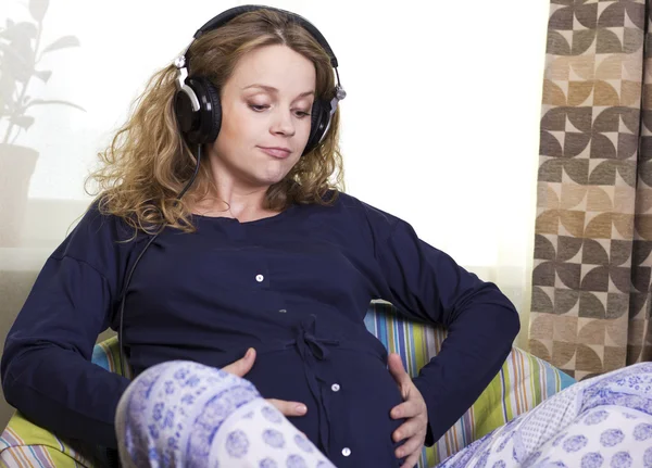 Pregnant woman listens to music. Woman in headphones