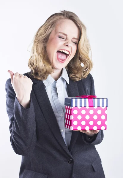 Happy affärskvinna med en gåva. Porträtt av en blondin i en jacka på en vit. — Stockfoto