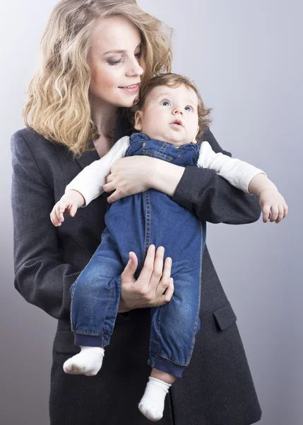 Bella bionda con il suo piccolo figlio sulle mani. Donna d'affari felice. Vita familiare. Bambini. Giovane madre — Foto Stock