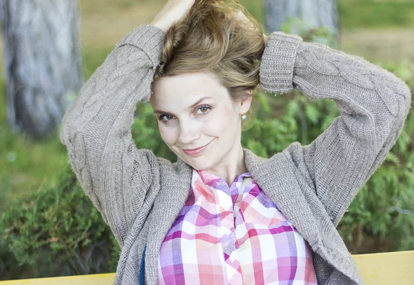 Belle fille souriante assise sur le porche d'une maison en bois.Belle blonde bouclée à l'extérieur. Portrait d'une femme heureuse . — Photo