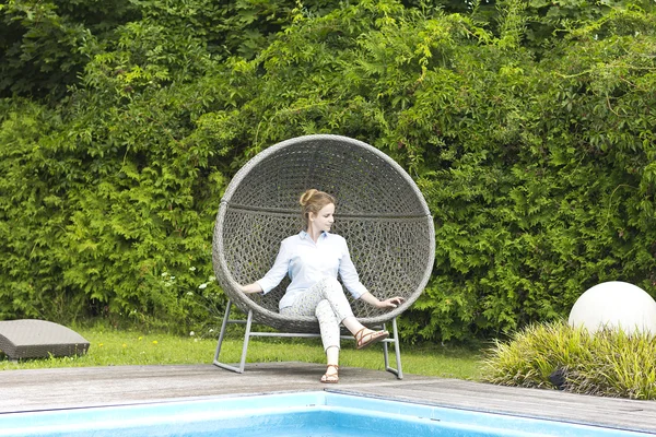 La hermosa rubia relajándose cerca de la piscina. La joven del spa. Hermosa mujer sonriente en una camisa azul . — Foto de Stock