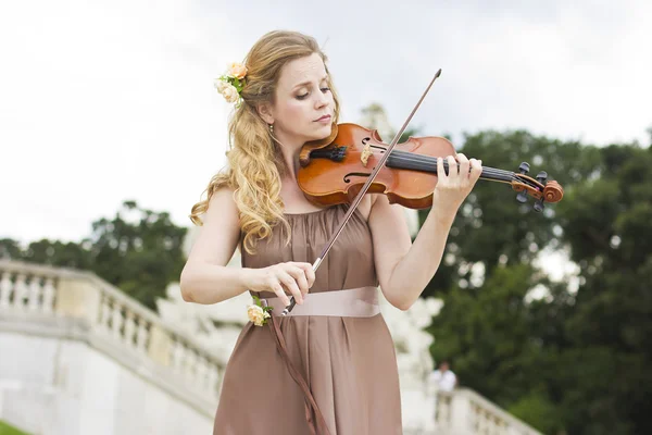 美丽的微笑的女孩，在户外的小提琴演奏。婚礼的音乐家。小提琴在开阔的天空下 — 图库照片