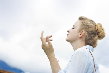 Güzel sarışın mavi gökyüzü arka plan üzerinde. Doğanın keyfini güzel kız. Taze dağ hava solumak