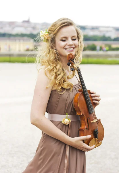 Beautiful smiling girl with a violin outdoor.Beautiful smiling girl playing on the violin outdoors. Musician for the wedding.Violin under the open sky — Stock Photo, Image