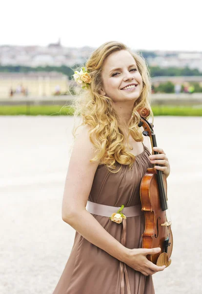 Menina sorridente bonita com um violino ao ar livre.Menina sorridente bonita tocando no violino ao ar livre. Músico para o casamento.Violino sob o céu aberto — Fotografia de Stock