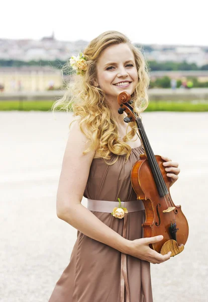 美丽的微笑的女孩与小提琴户外。美丽的微笑的女孩在户外拉小提琴。婚礼的音乐家开放天空下的小提琴 — 图库照片