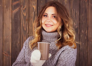 Bir fincan sıcak çayla gülümseyen kadın.