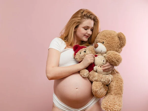 穿着粉色背景的泰迪熊的孕妇 — 图库照片