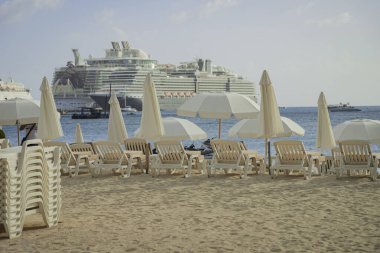 Plajda beyaz plaj sandalyeleri ve şemsiyeler