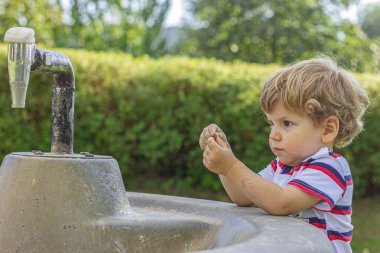 Küçük çocuk suyla oynuyor.
