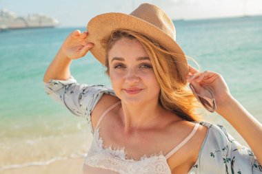 Kumsalda şapkalı genç sarışın kadın.