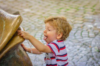 Küçük çocuk sokakta suyla oynuyor.